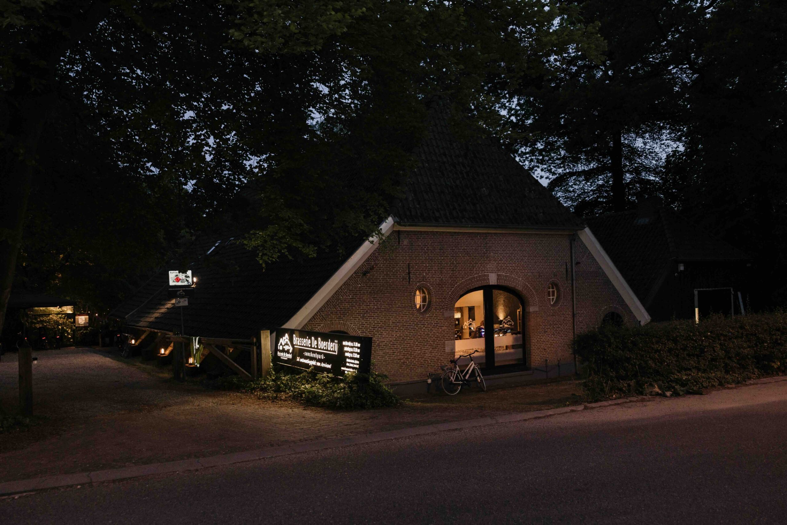 Achteraanzicht van Brasserie de Boerderij vanaf de parkweg 's avonds